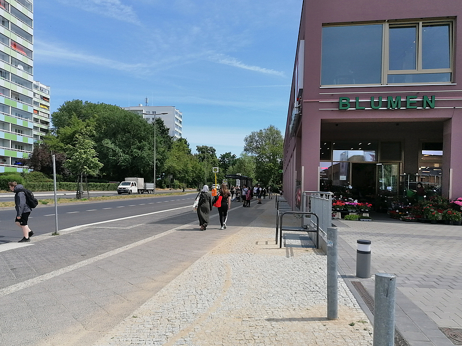 Straße, breiter Gehweg mit Pollern und Fahrradbügeln, Einkaufszentrum