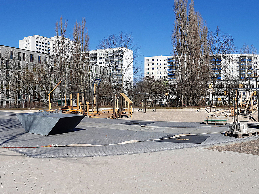 Spielplatz mit Tischtennisplatte, dahinter Wohnbauten im Frühling