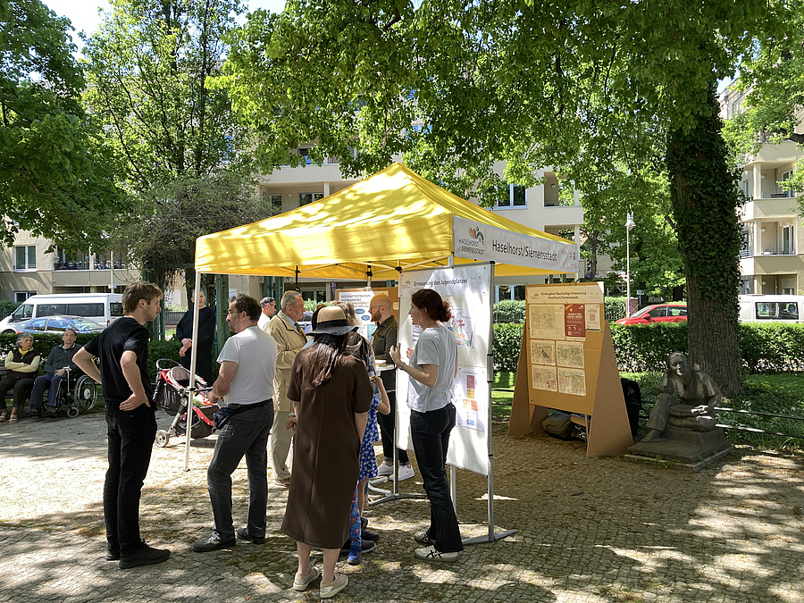 Pavillon mit Informationen und Menschen auf grünem Platz