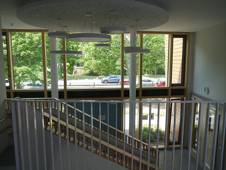 Blick über Treppenabsatz zur Fensterfront, runde Tellerlampen in verschiedenen Größen hängen in verschiedenen Höhen