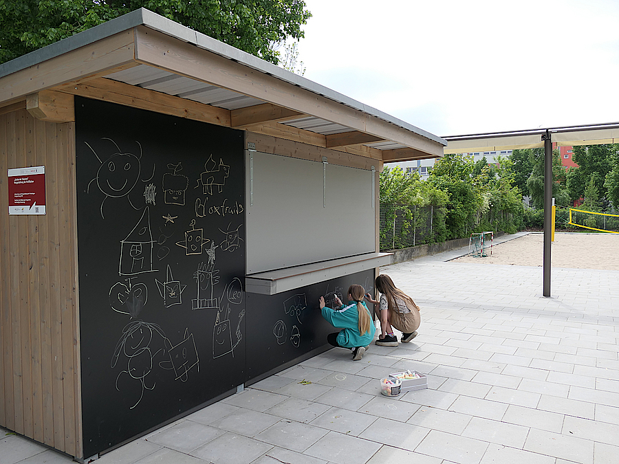 2 Mädchen malen auf der Tafeloberfläche der neuen Außenküche im Garten von Haus Babylon
