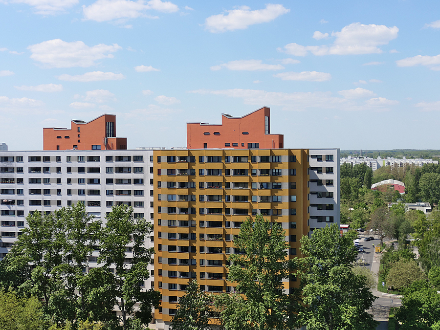 Blick vom Dach auf weißes und gelbes Hochhaus mit Dachstudios