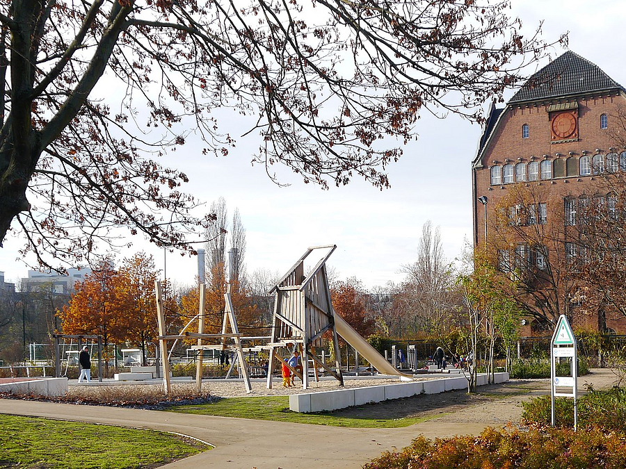 Weggabelung, Spielplatz, Bäume, Beete, Backsteingiebel