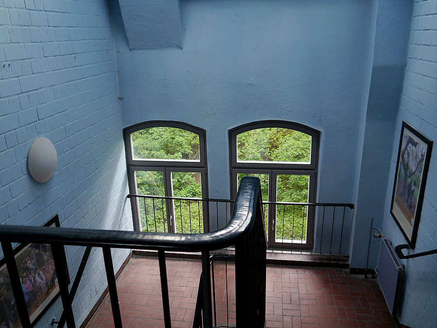 Treppenhaus mit zwei alten Fenstern und hellblauen Wänden