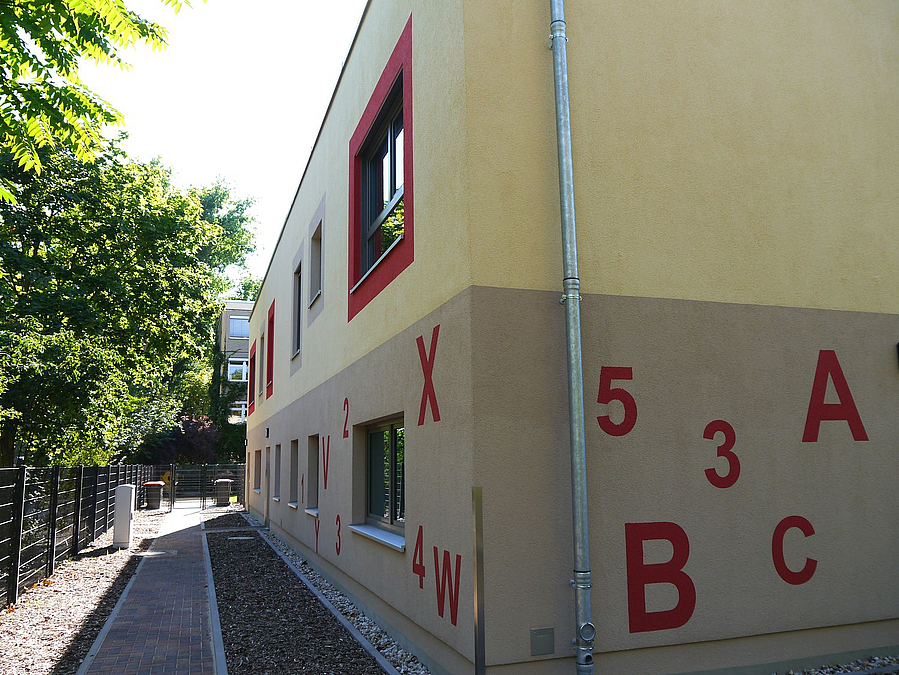 Beige-Graue Gebäudeecke mit Buchstaben und Zahlen auf der Wand im Erdgeschoss