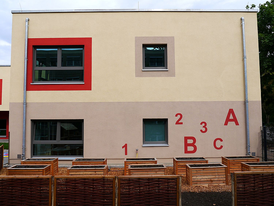 Gebäudegiebel mit 2 Etagen in Grau und Beige, Zahlen und Buchstaben, Holzkisten