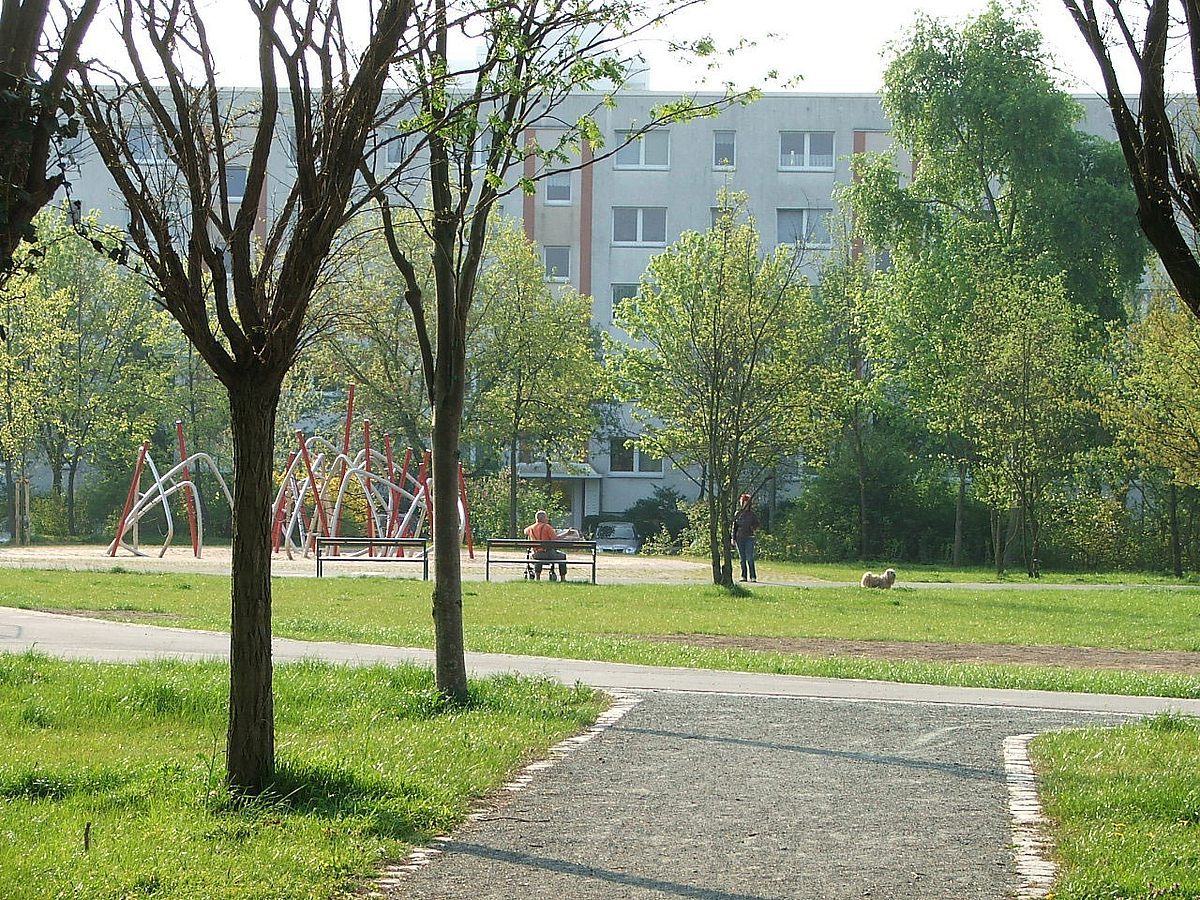 Park mit Kletterspielplatz und Plattenbau im Hintergrund