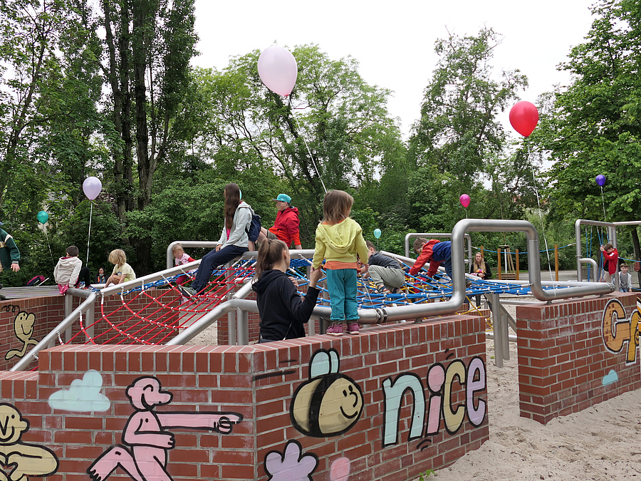 Kinder auf bunt gestalteten Klinkermauern mit Netzen und Luftballons