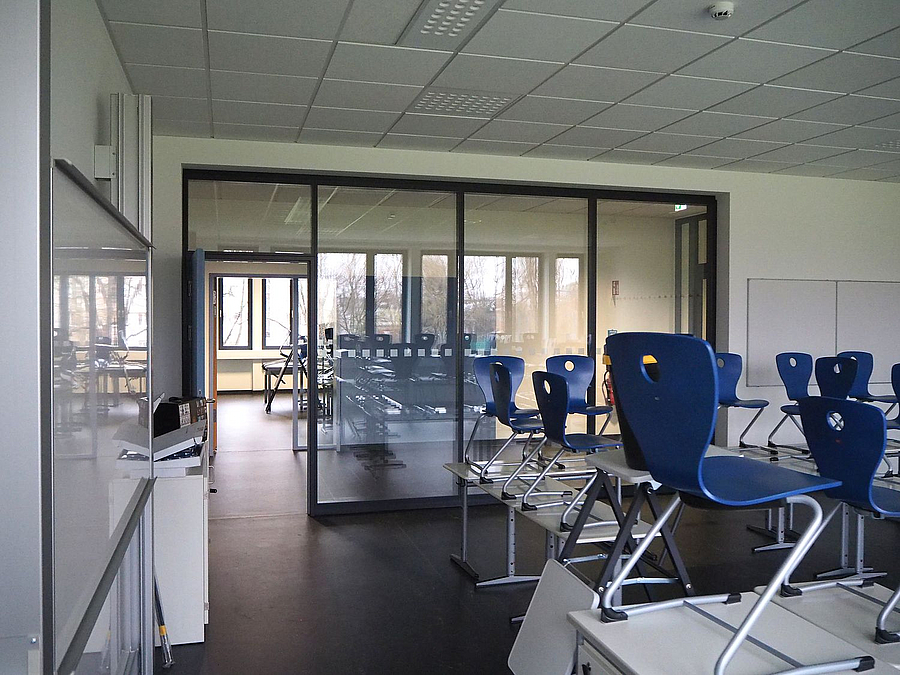 Klassenraum mit hochgestellten Stühlen, Blick über den Flur in weiteren Raum