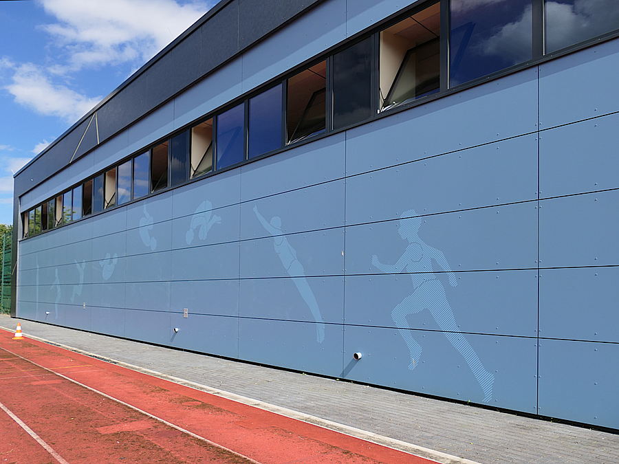 Sporthallen-Außenwand mit Bild eines springenden Turners in verschiedenen Phasen