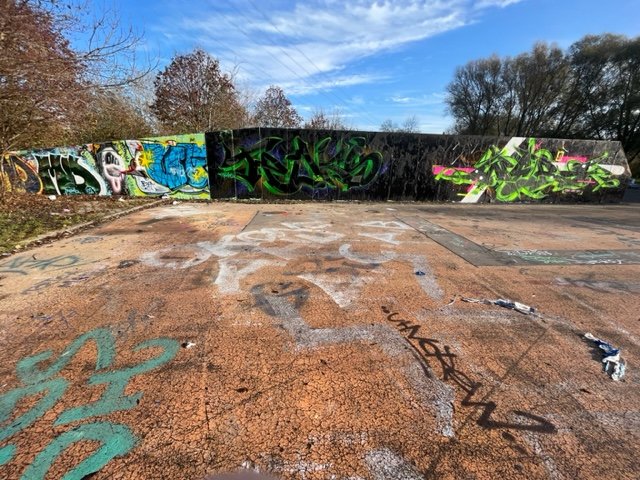 Roter, kaputter Asphalt, Mauer mit Graffiti